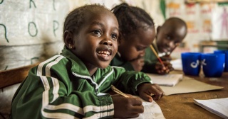 Un enfant prend des notes en classe.