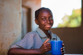 Une fille avec un mug de nourriture à l'école.