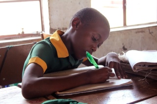 Un enfant prend des notes en classe.